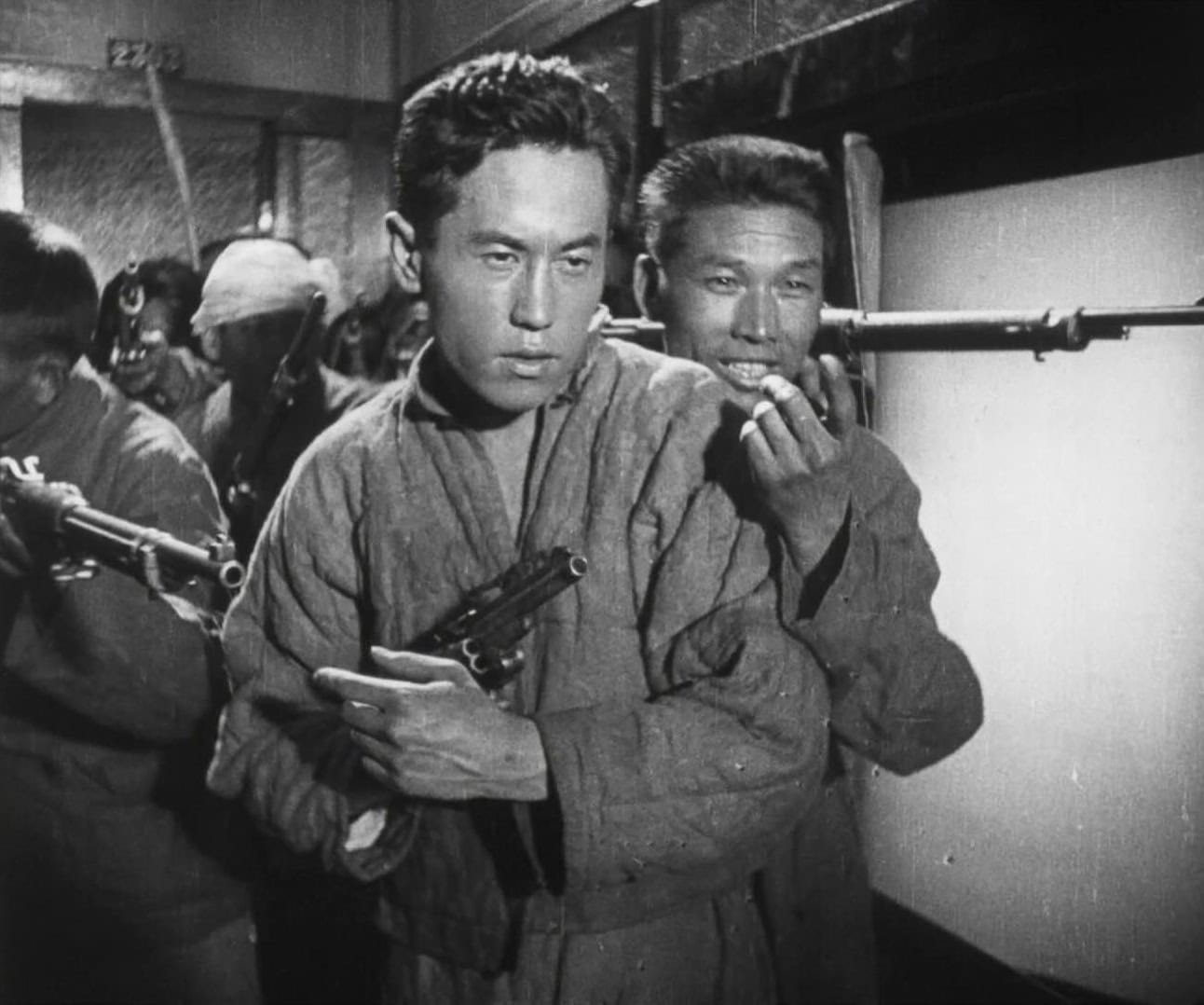 Black and white photo of soldiers in a tense moment during wartime, with one holding a pistol and others in the background.
